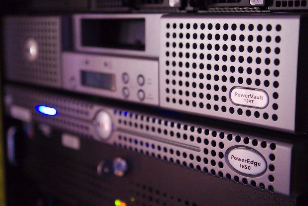 Close-up of rack-mounted computer servers with perforated metal fronts and a glowing blue light