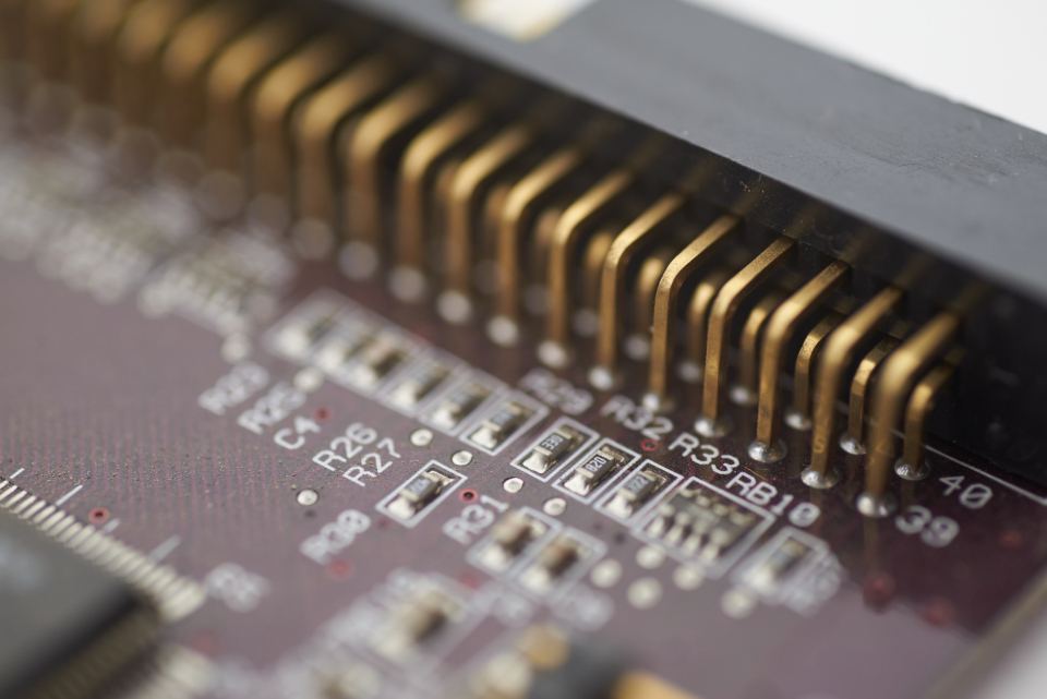 Close-up of a circuit board with gold connector pins and small surface-mounted components