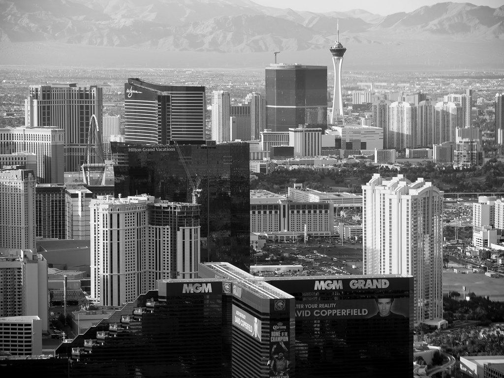 Black-and-white aerial view of Las Vegas high-rise towers and the Strat tower with mountains behind