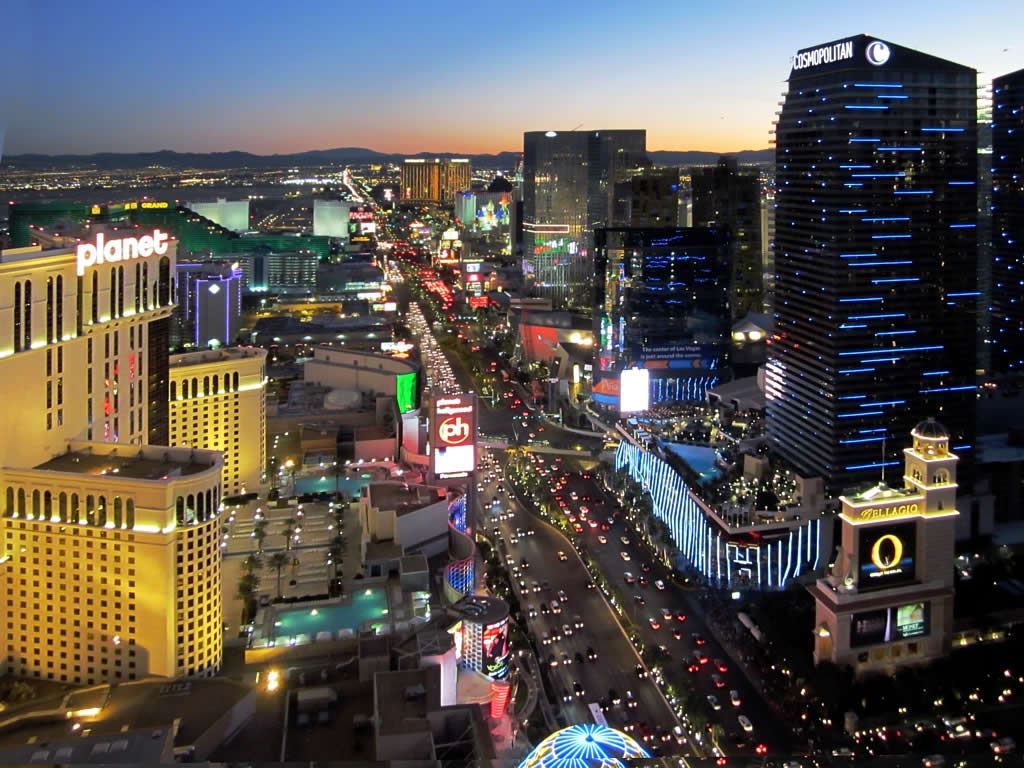 Aerial view of the Las Vegas Strip at dusk with lit casino towers and heavy traffic on the boulevard