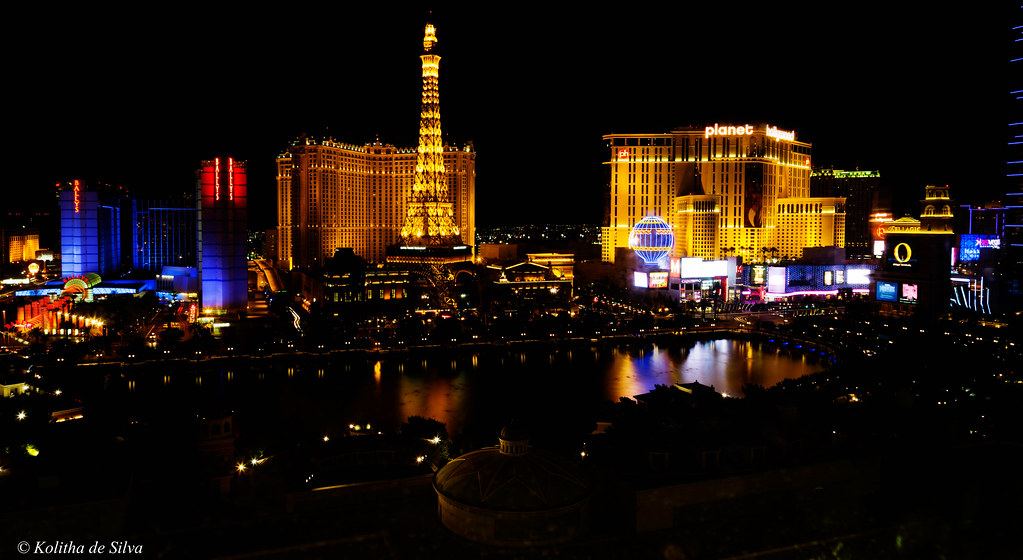 Las Vegas Strip casinos and an Eiffel Tower replica lit up at night behind a dark lake