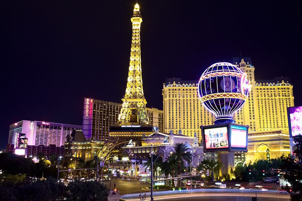 The Las Vegas Strip at night with the illuminated Eiffel Tower replica, a hot air balloon sign and casino hotels