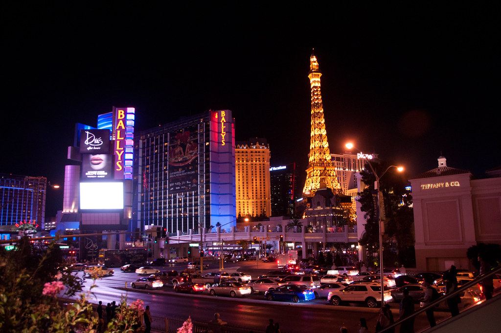 The Las Vegas Strip at night, with lit hotel towers, an Eiffel Tower replica and traffic on the boulevard
