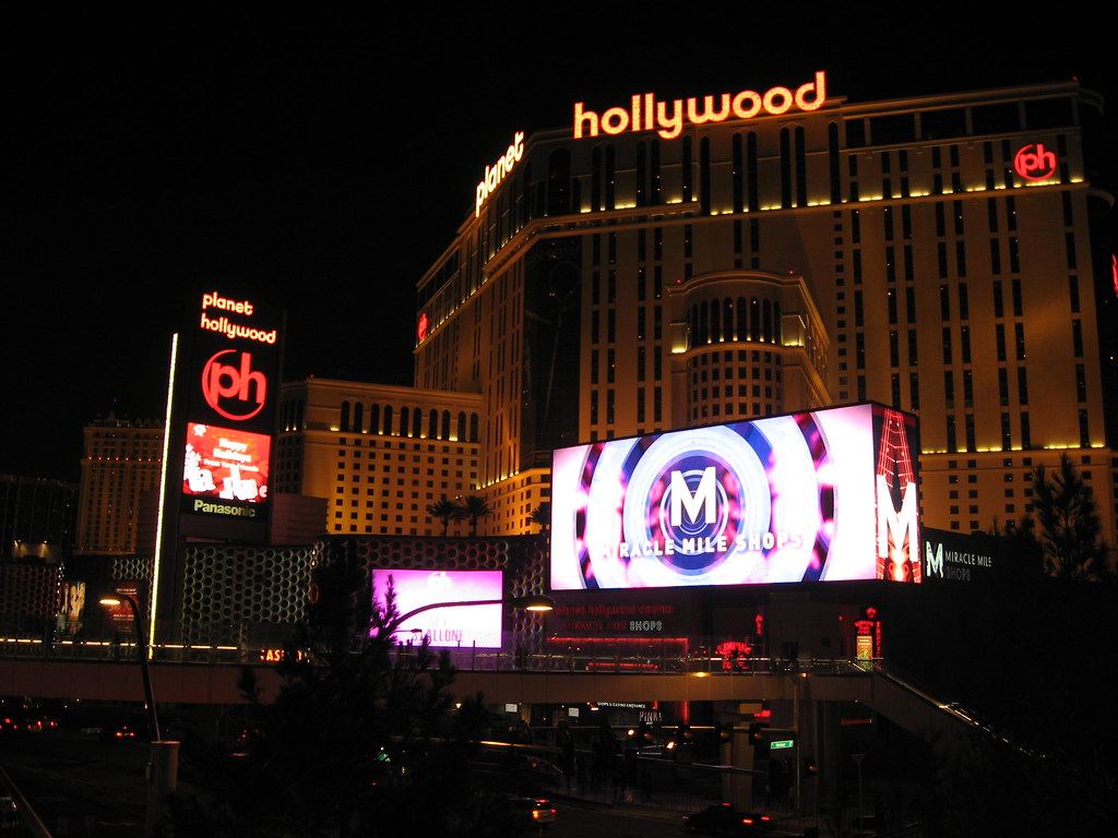 Planet Hollywood resort tower and Miracle Mile Shops video billboard lit up at night above a Las Vegas street