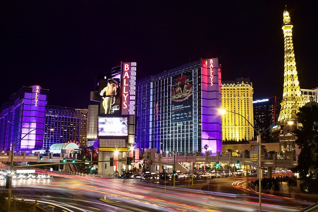 Las Vegas Strip at night with lit casino towers, a replica Eiffel Tower and streaks of traffic light