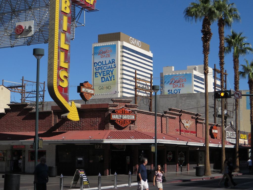 White hotel towers marked Grand rise behind a brick Harley-Davidson store, palm trees and a Bills sign downtown