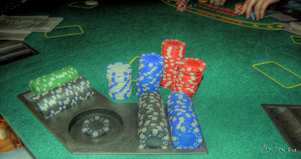 Stacks of colorful casino chips in a chip tray on a green felt gaming table