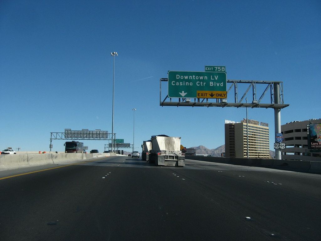 Freeway traffic under an overhead sign for the Downtown LV and Casino Center Blvd exit on a clear day