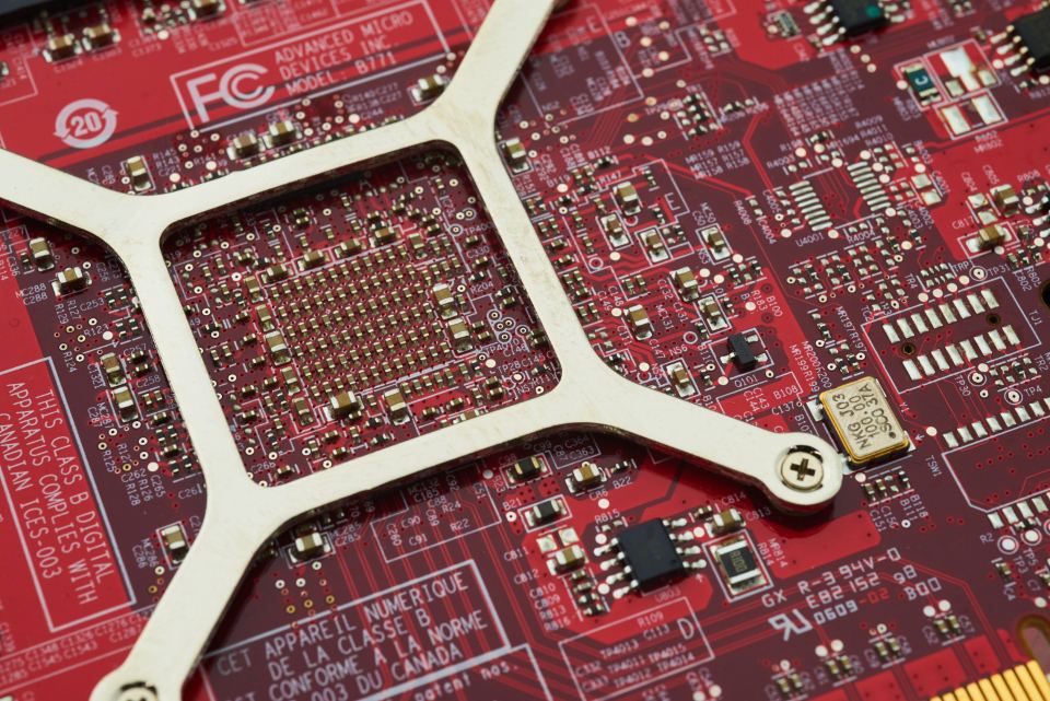 Close-up of a red computer circuit board with a metal bracket, microchips and small electronic components