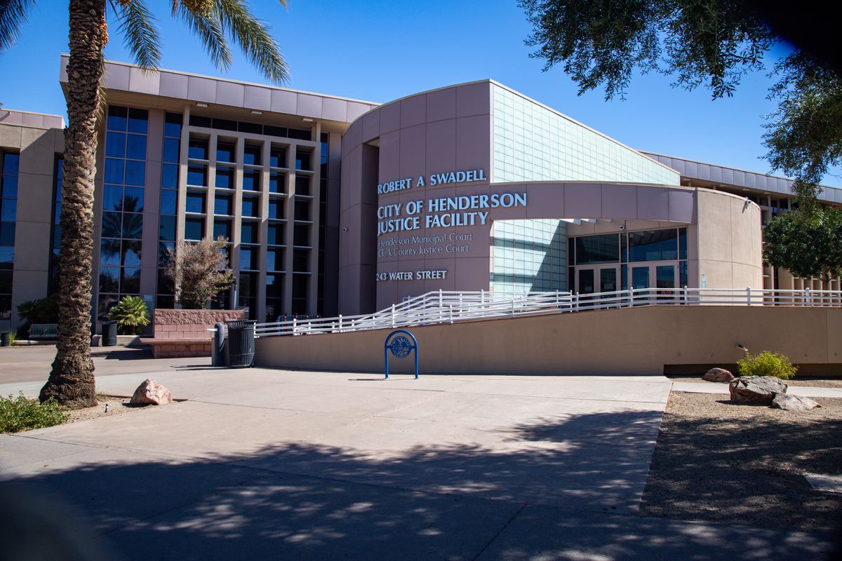 Exterior of the City of Henderson Justice Facility, a beige and glass building with palm trees, under a blue sky