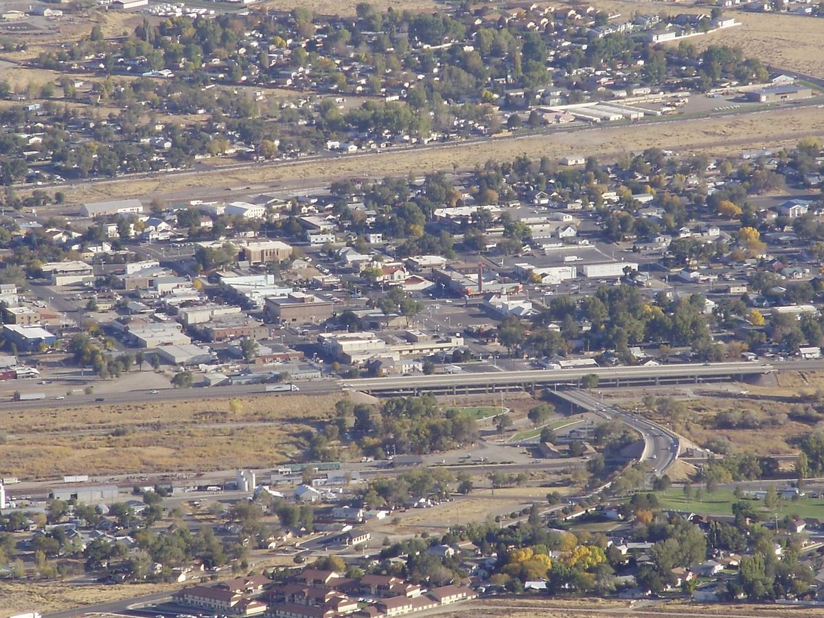 Aerial view of a small desert town with low buildings, tree-lined streets, an overpass and railroad tracks
