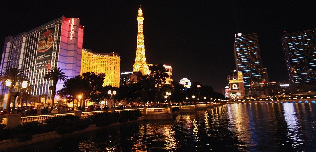 Las Vegas Strip hotels and a lit Eiffel Tower replica reflected in a lake at night