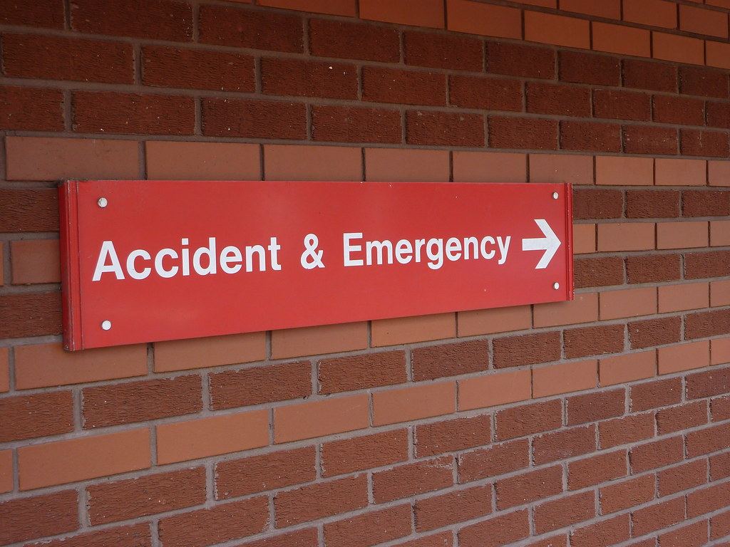 Red Accident & Emergency sign with a white arrow mounted on a red brick wall