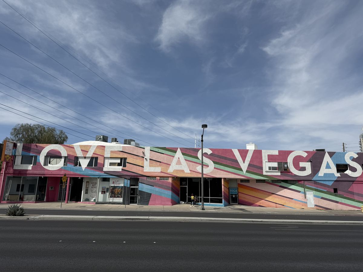A long building painted with colorful diagonal stripes and large white letters reading LOVE LAS VEGAS beside a street