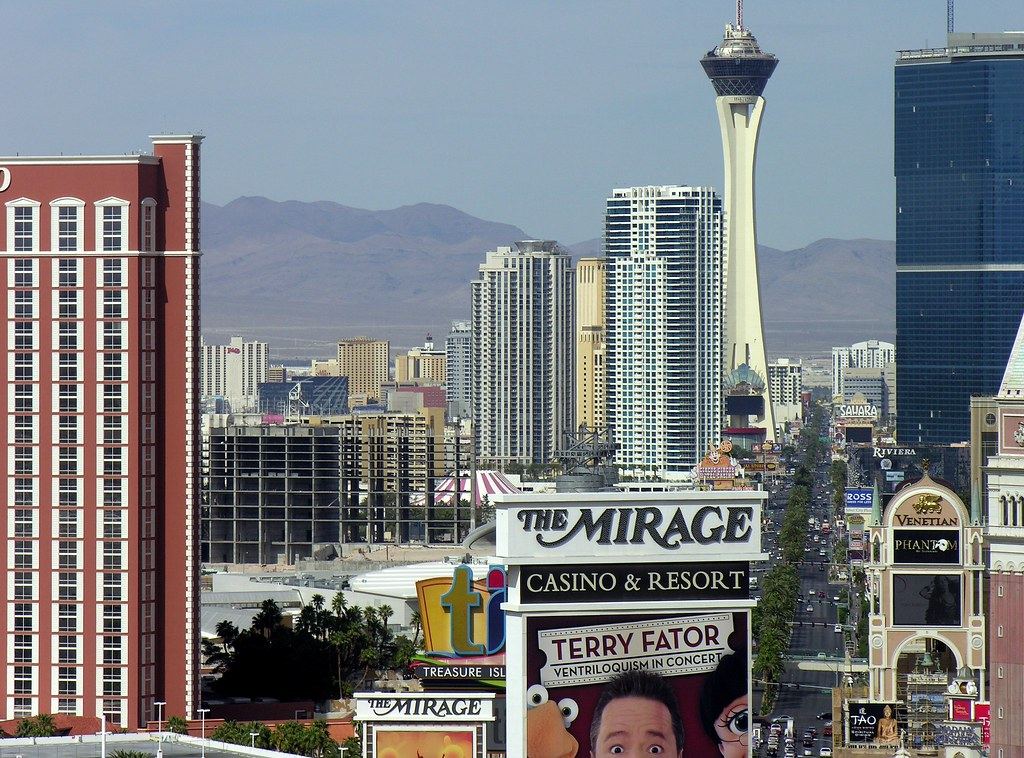 Las Vegas Strip high-rises and casino signs, with the Stratosphere tower and desert mountains in the distance