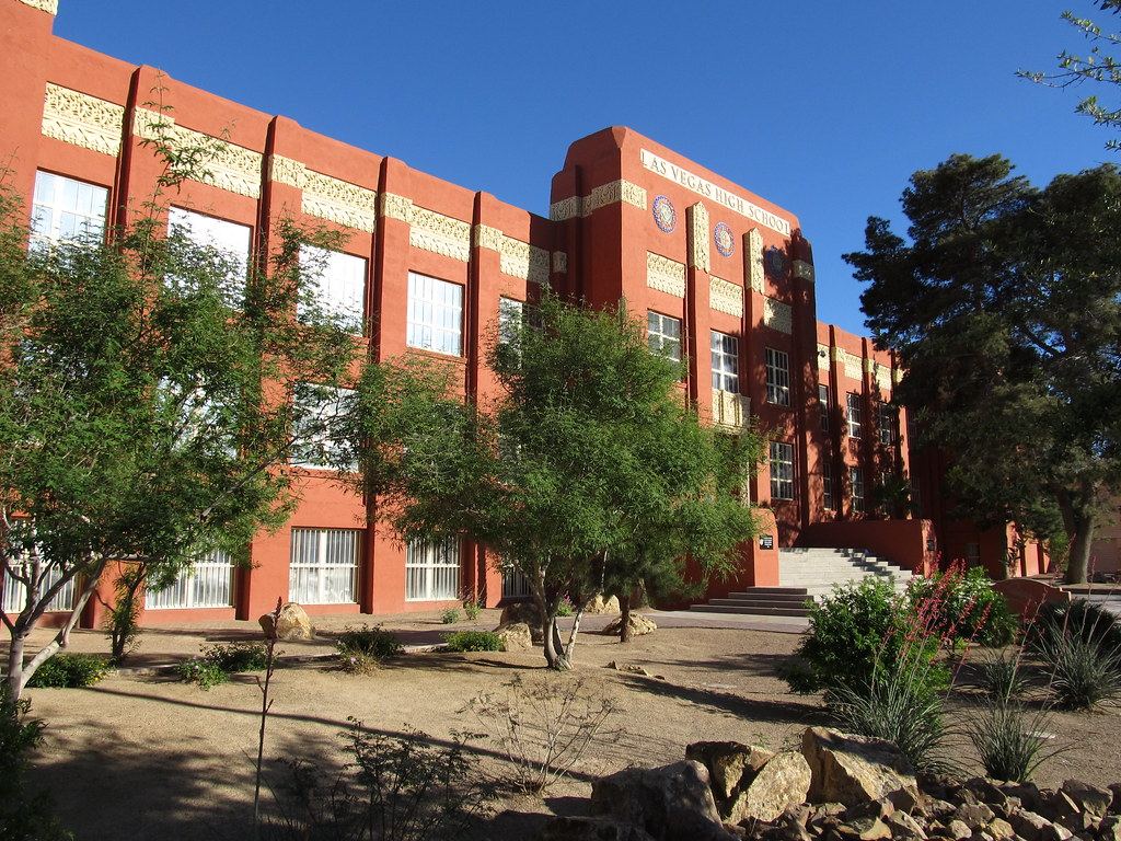 Red Art Deco school building with ornate trim, front steps and desert landscaping under a clear blue sky