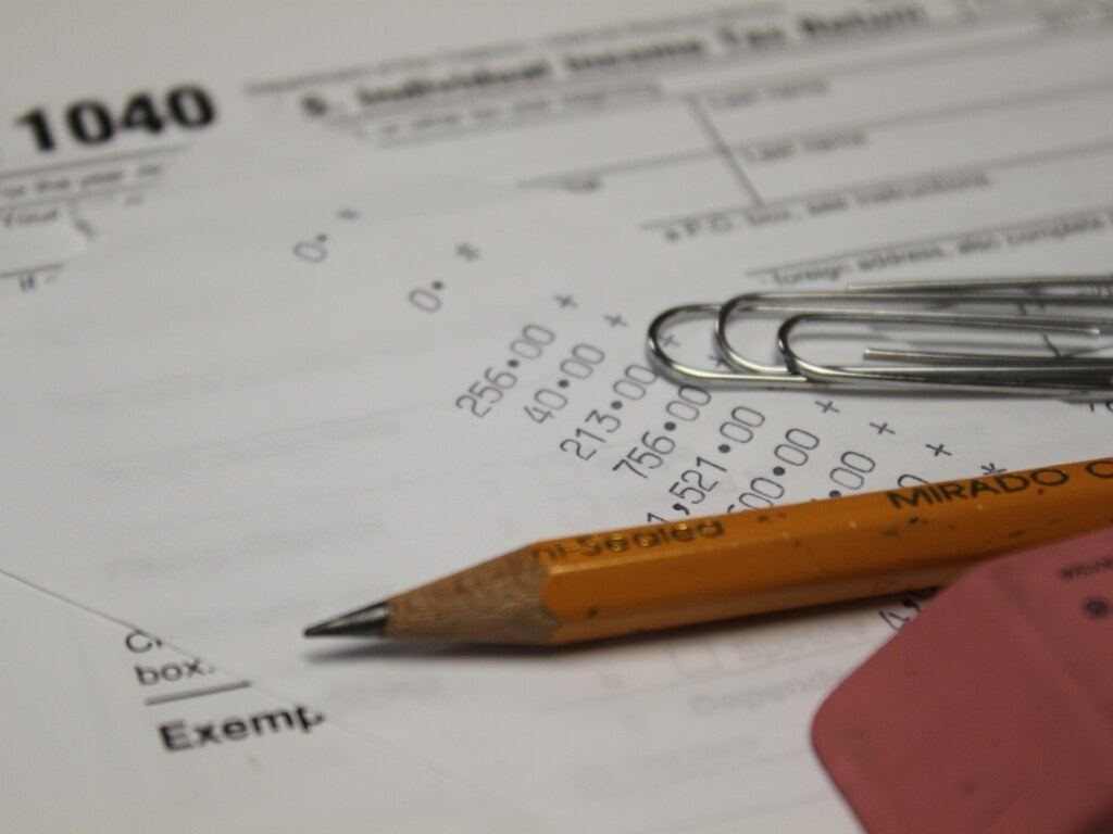 Close-up of a 1040 tax form with an adding-machine tape, a yellow pencil, paper clips and a pink eraser