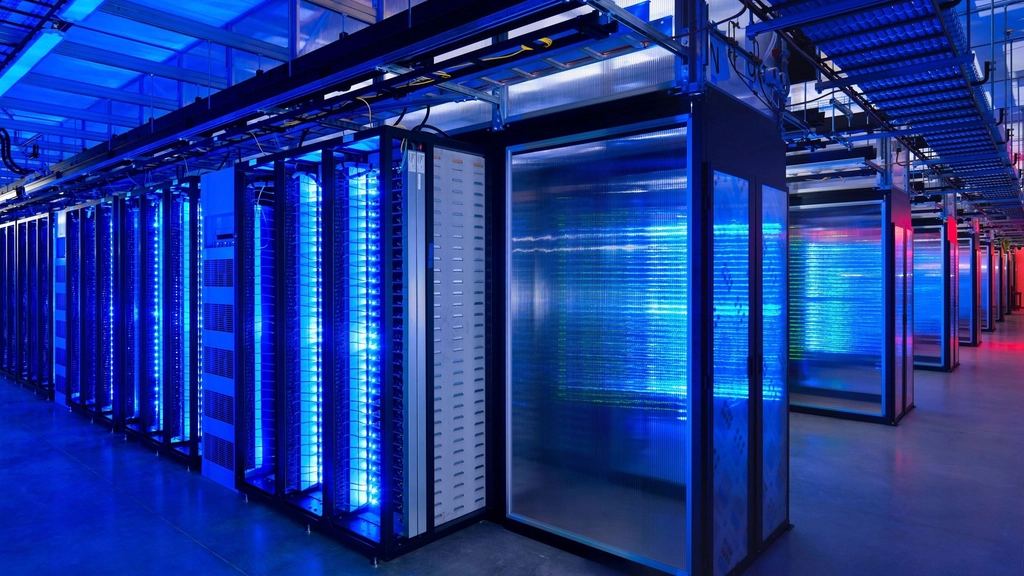 Rows of server racks glowing with blue light inside a large data center with overhead cable trays