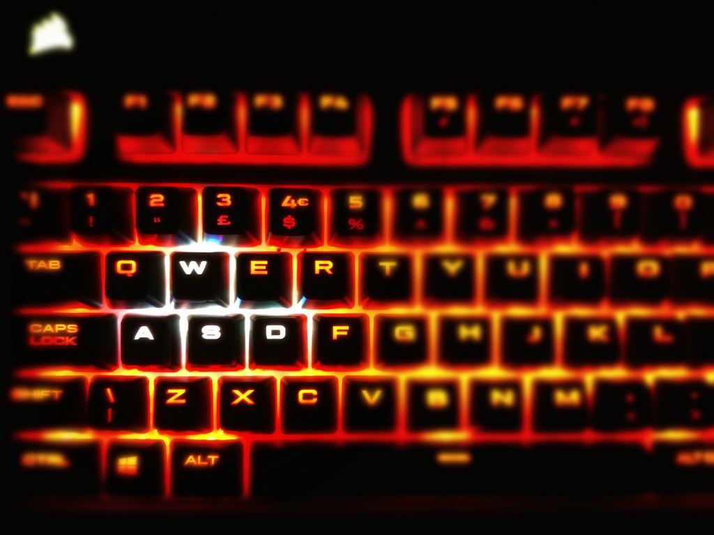 Close-up of a black computer keyboard with keys glowing in bright red and orange backlighting