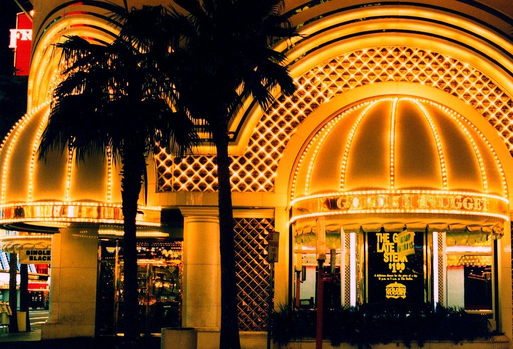 Gold-lit domed awnings and lattice facade of the Golden Nugget casino at night, framed by palm trees