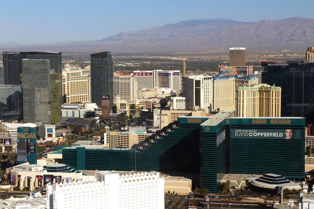 Aerial view of Las Vegas Strip resort towers with desert mountains in the distance under a clear sky