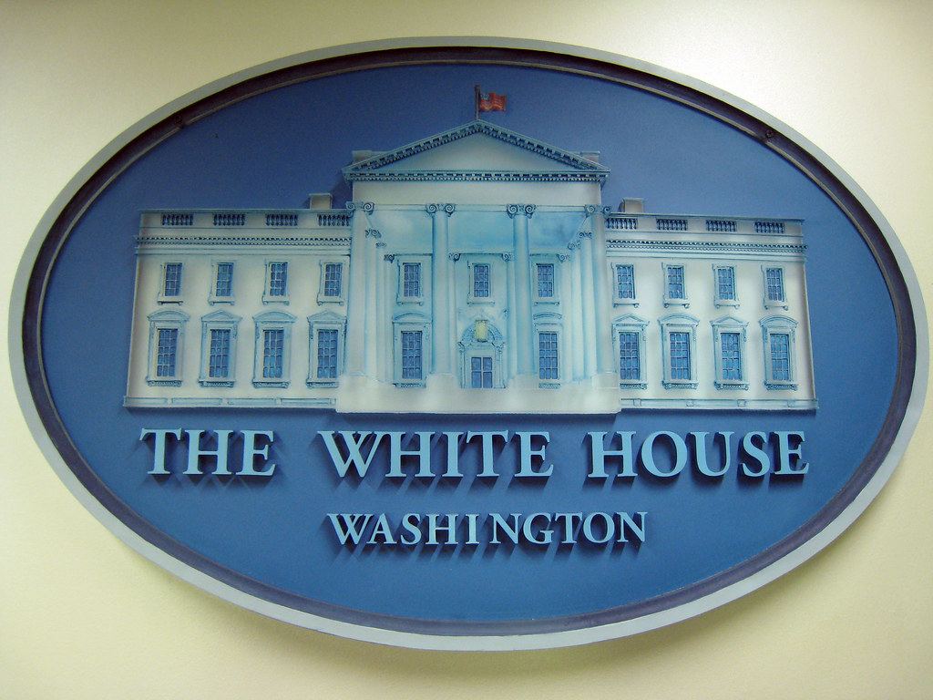 Oval blue plaque with a sculpted White House facade and the words The White House Washington