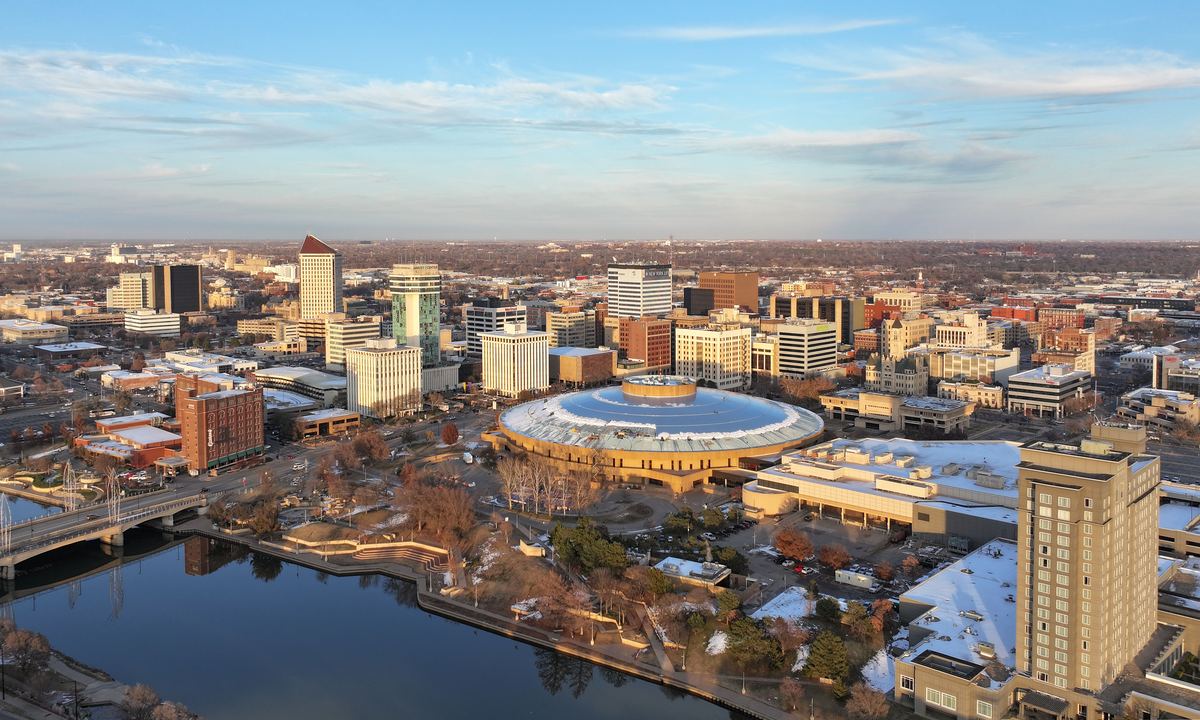 Aerial view of a downtown skyline with a round domed building beside a river at sunset