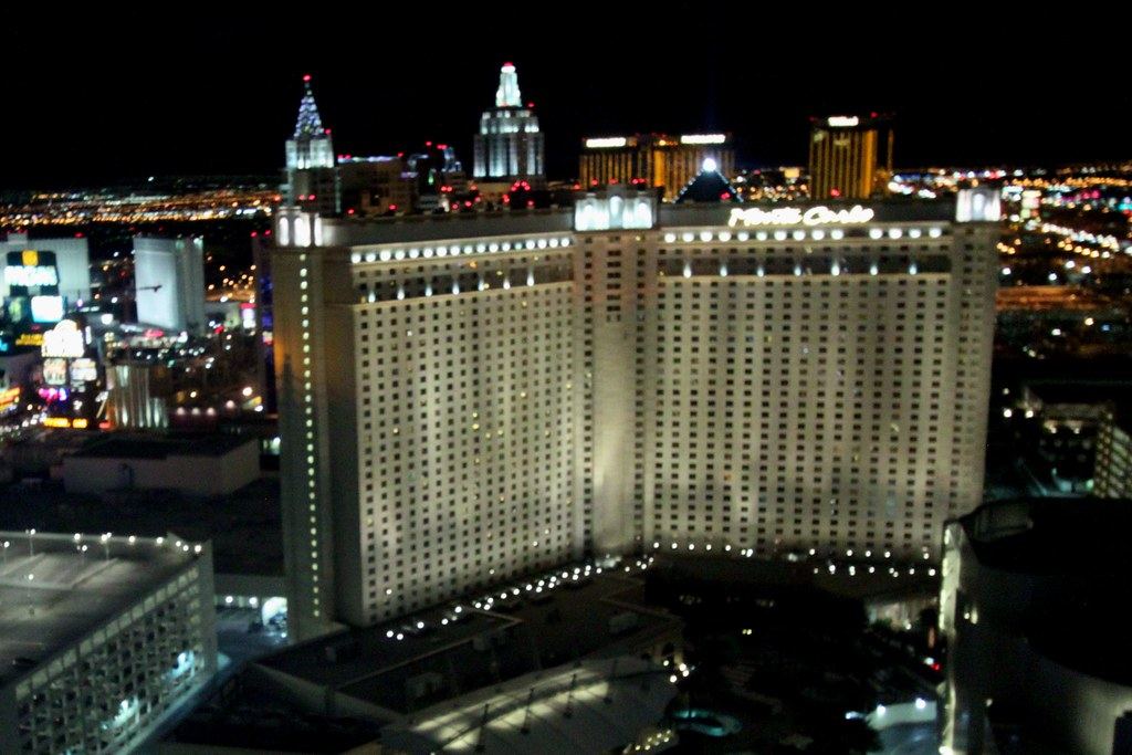 A large lit hotel tower and other resort buildings glow against the night sky along the Las Vegas Strip