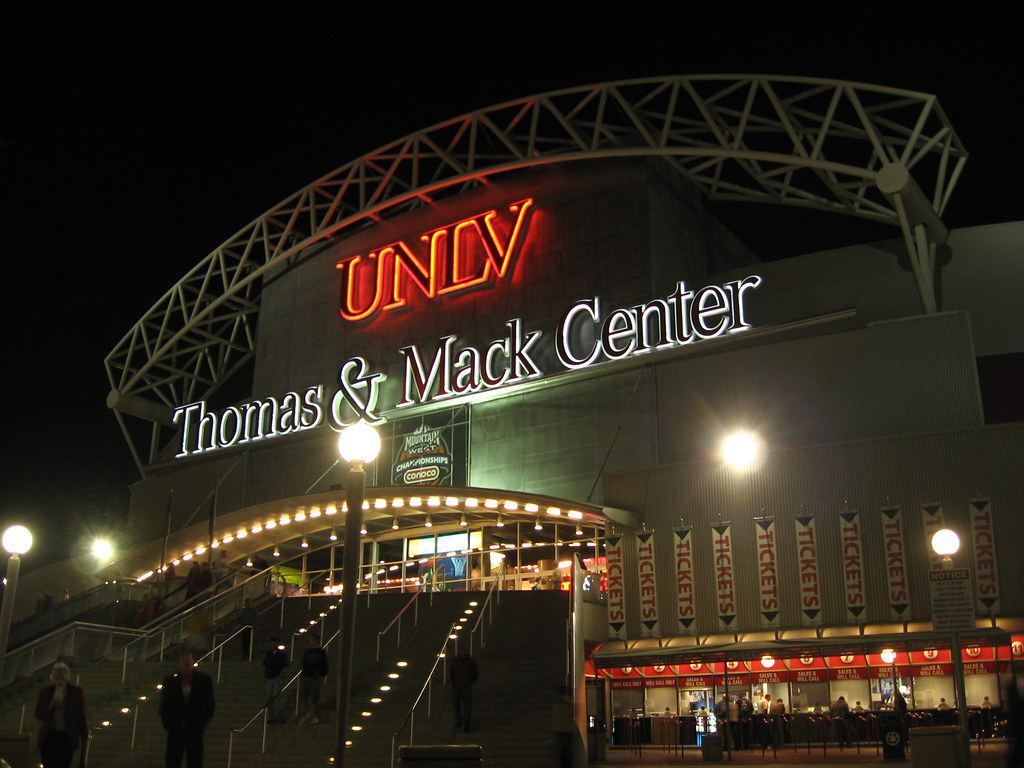 The Thomas & Mack Center arena at UNLV lit up at night, with its entrance stairs and ticket windows