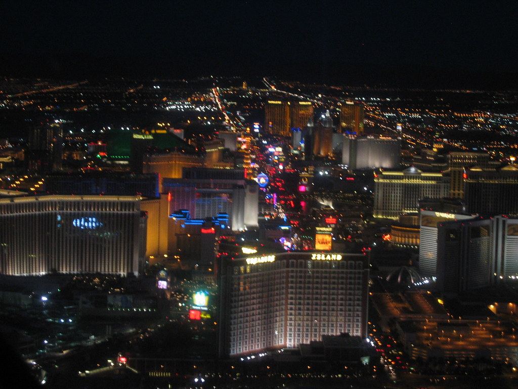 Aerial night view of the Las Vegas Strip, with brightly lit casino hotel towers stretching toward the horizon