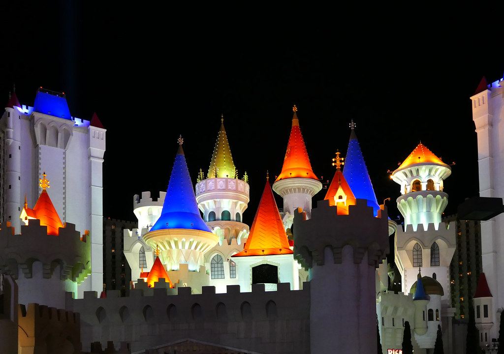 Castle-style towers with brightly lit red, blue and gold spires against a dark night sky