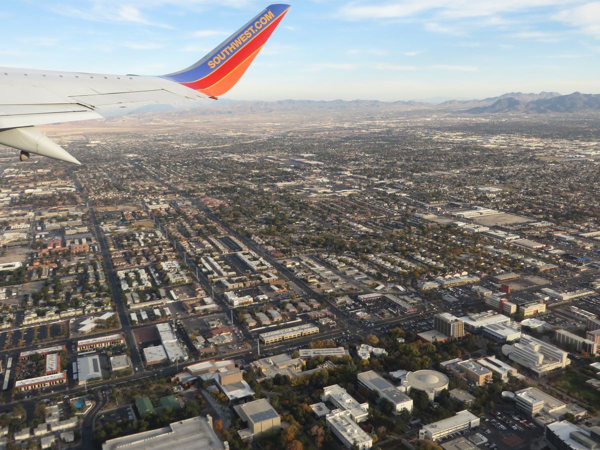 Aerial view of Las Vegas and the UNLV campus seen past an airplane wingtip, with mountains on the horizon